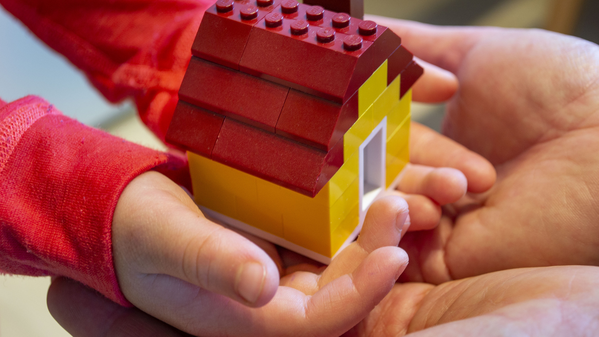 Barn håller i ett hus av lego.